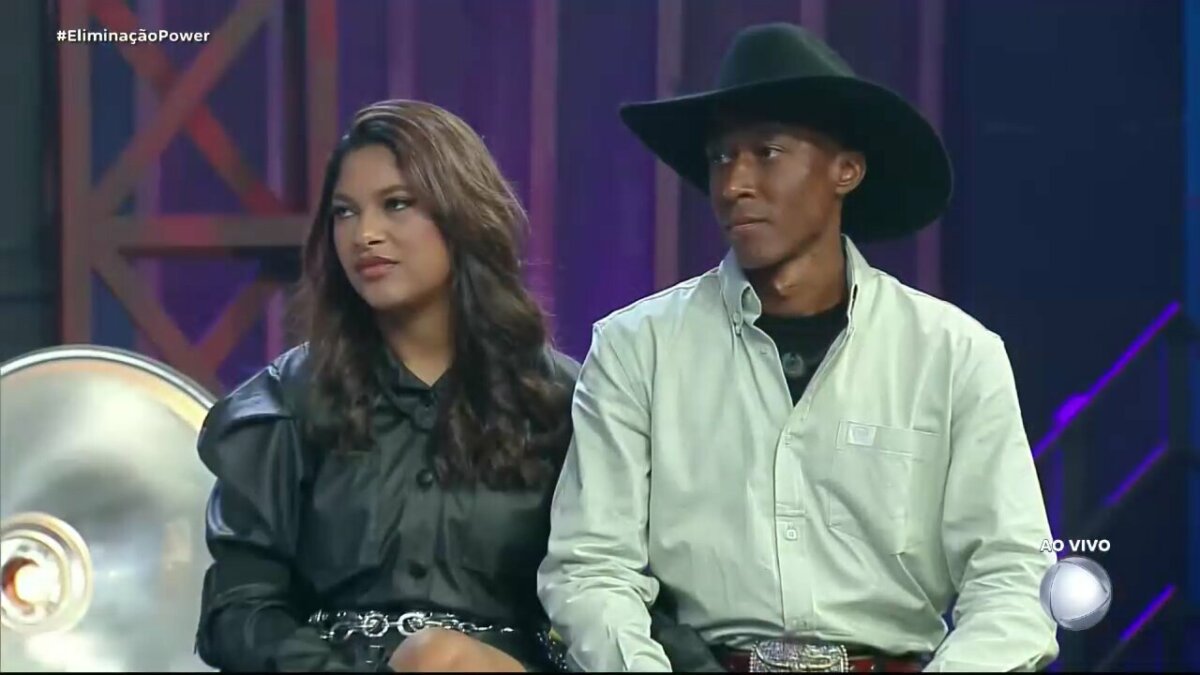 Emilyn e Neguinho sentados no palco do Power Couple