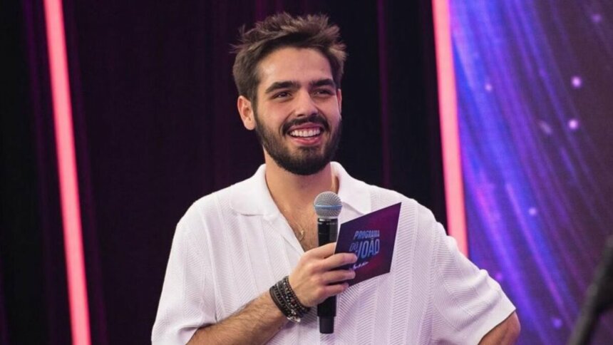 João Guilherme Silva com microfone e ficha nas mãos, em trecho do Programa do João na Band