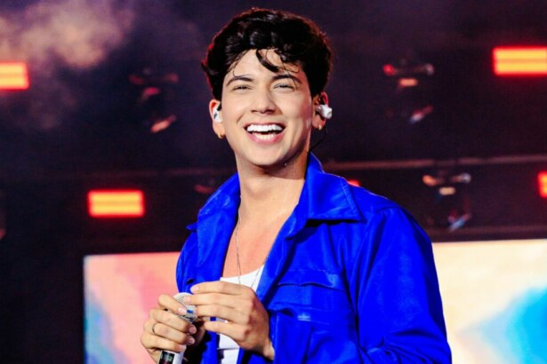 Léo Foguete, vestindo uma jaqueta azul, sorridente, em trecho de apresentação no São João de Petrolina