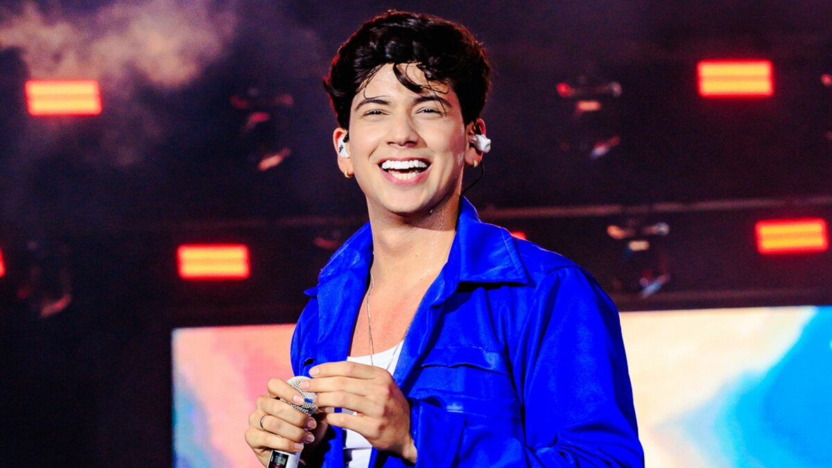 Léo Foguete, vestindo uma jaqueta azul, sorridente, em trecho de apresentação no São João de Petrolina