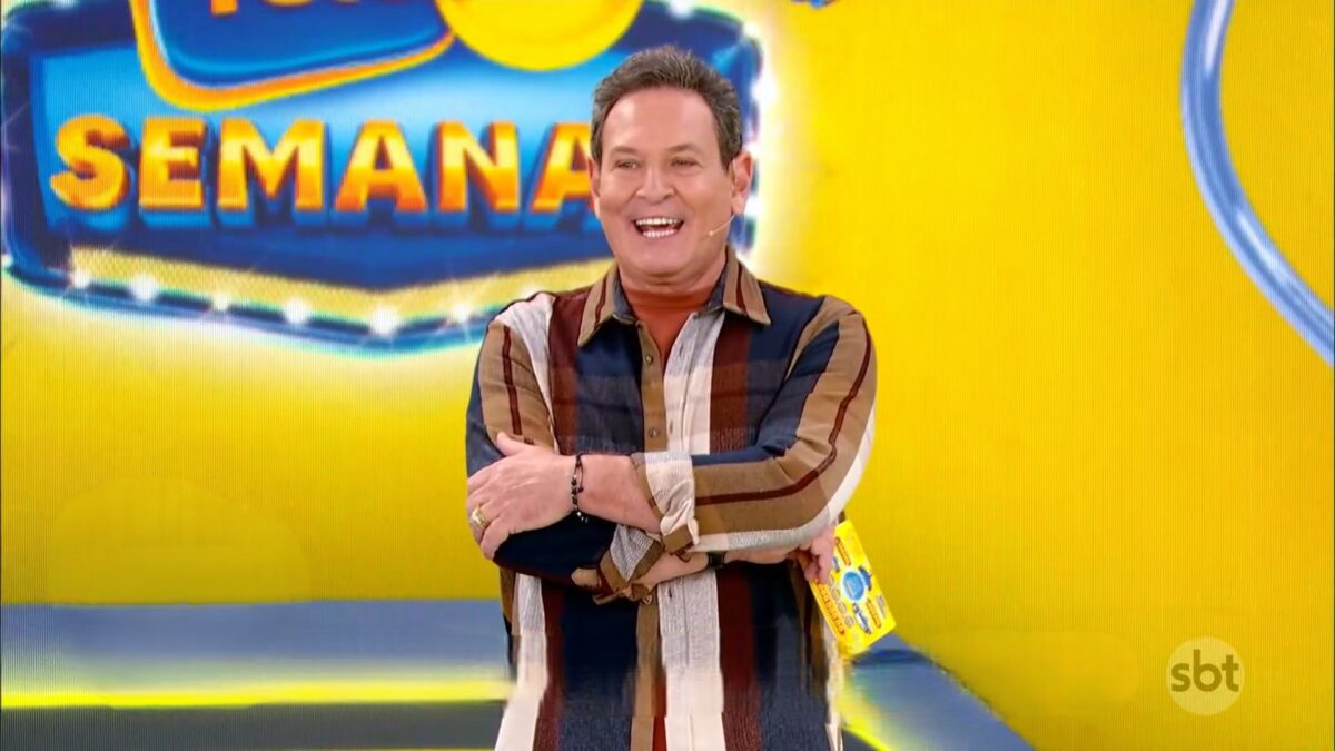 Luis Ricardo com os braços cruzados e sorrindo no cenário da Tele Sena Semanal edição 54