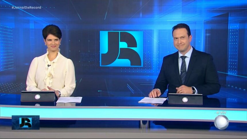 Mariana Godoy e Edu Ribeiro sorridentes na bancada do Jornal da Record