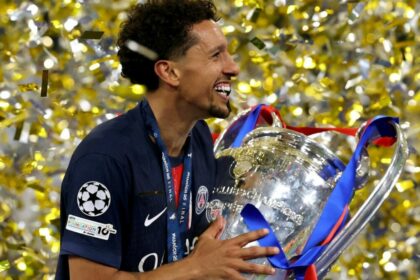 Marquinhos, com a camisa do PSG, segurando a taça da Liga dos Campeões, em meio a chuva de papel picado