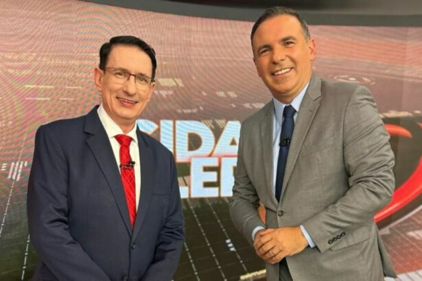 Roberto Guastelli e Gottino posando em frente ao telão no cenário do Cidade Alerta