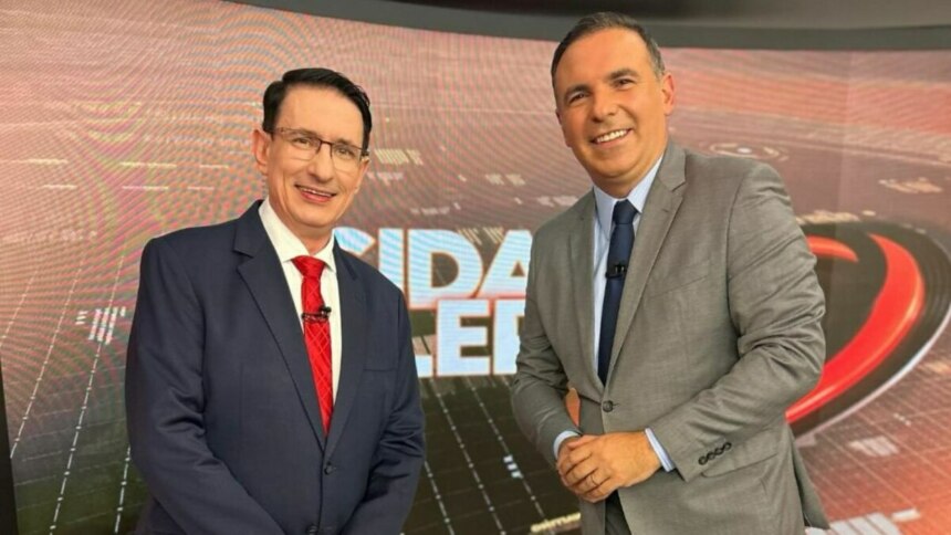Roberto Guastelli e Gottino posando em frente ao telão no cenário do Cidade Alerta