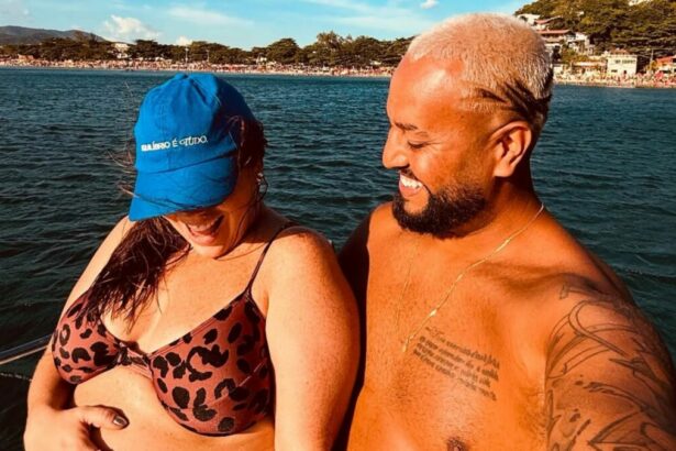 Tati Machado e marido o em trecho de foto na gravidez, em passeio na praia