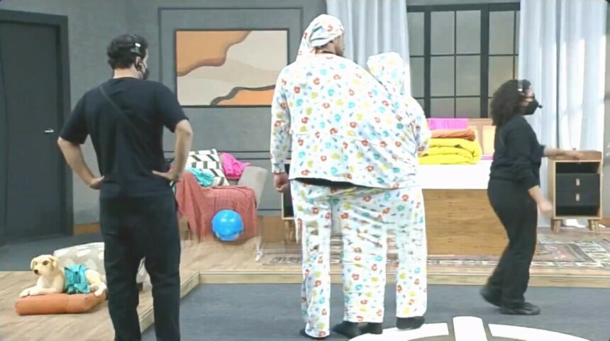 Victor e Rayanne vestidos por um mesmo pijama caminham no cenário da Prova dos Casais do Power Couple Brasil 7