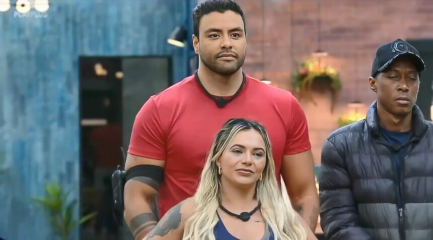 Antony por trás de Ana Paula na sala do Power Couple Brasil 7. eles estão com semblante sério após disputa na 6ª Prova dos Homens