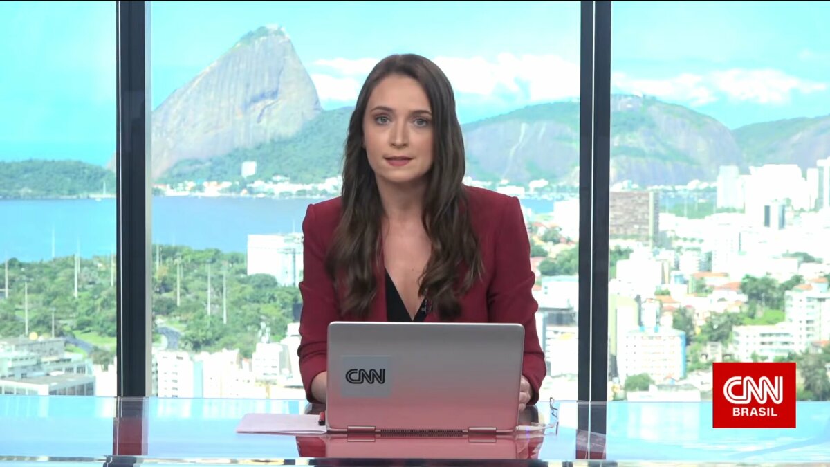 Amábyle Sandri sentada na bancada da CNN Brasil na sucursal do Rio de Janeiro