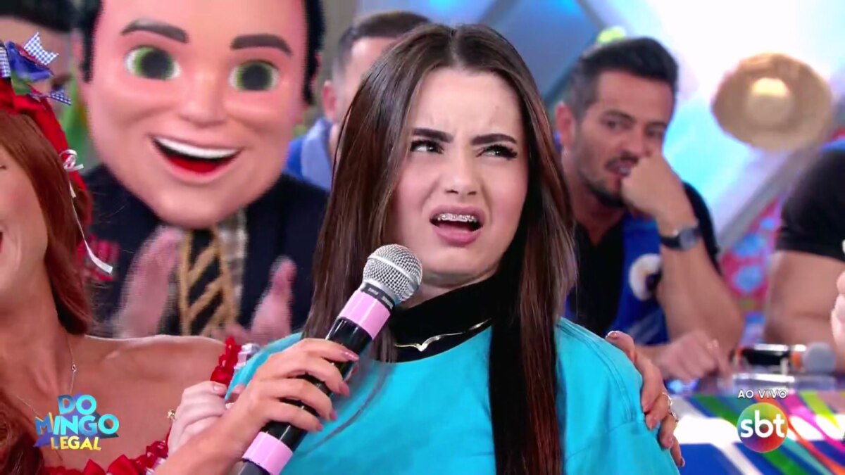 Mulher, vestindo a camisa do time azul, faz cara feia para Celso Portiolli após errar pergunta simples no Domingo Legal