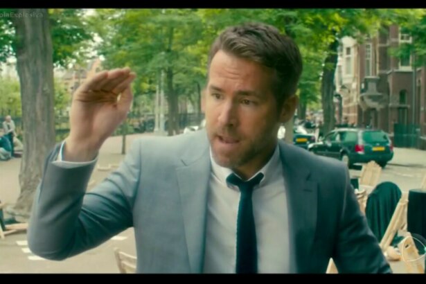 Ryan Reynolds de terno e gravata em cena do filme Dupla Explosiva