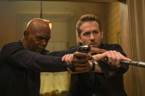 Samuel L. Jackson e Ryan Reynolds segurando armas em cena do filme Dupla Explosiva