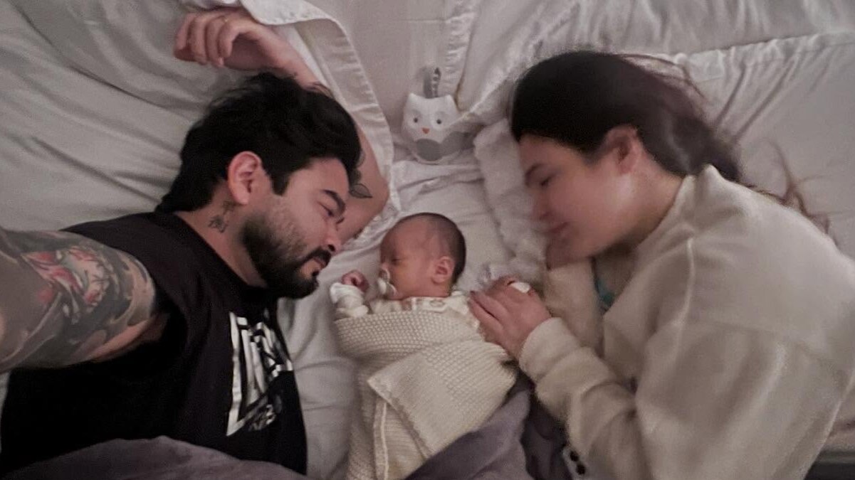 Davi Yudi deitado ao lado de Yudi e sua esposa