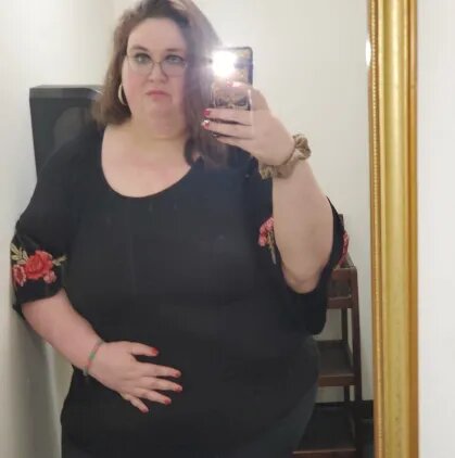 Jeanne veste roupa preta e tira fotos em frente a um espelho mostrando seu desenvolvimento após o  Quilos Mortais
