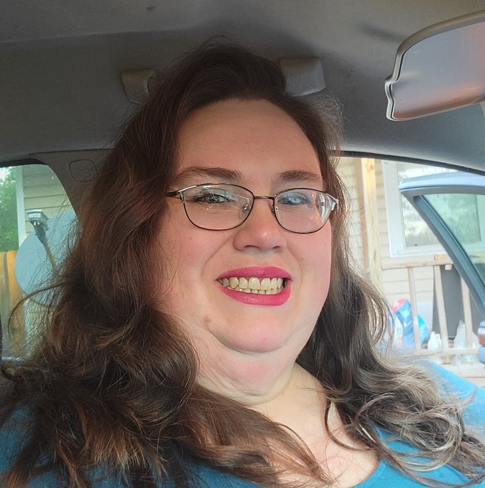 Jeanne sorridente com óculos de grau dentro de um carro 