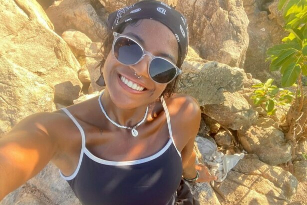 Juliana Marins sorrindo com óculos de sol próximo a umas pedras