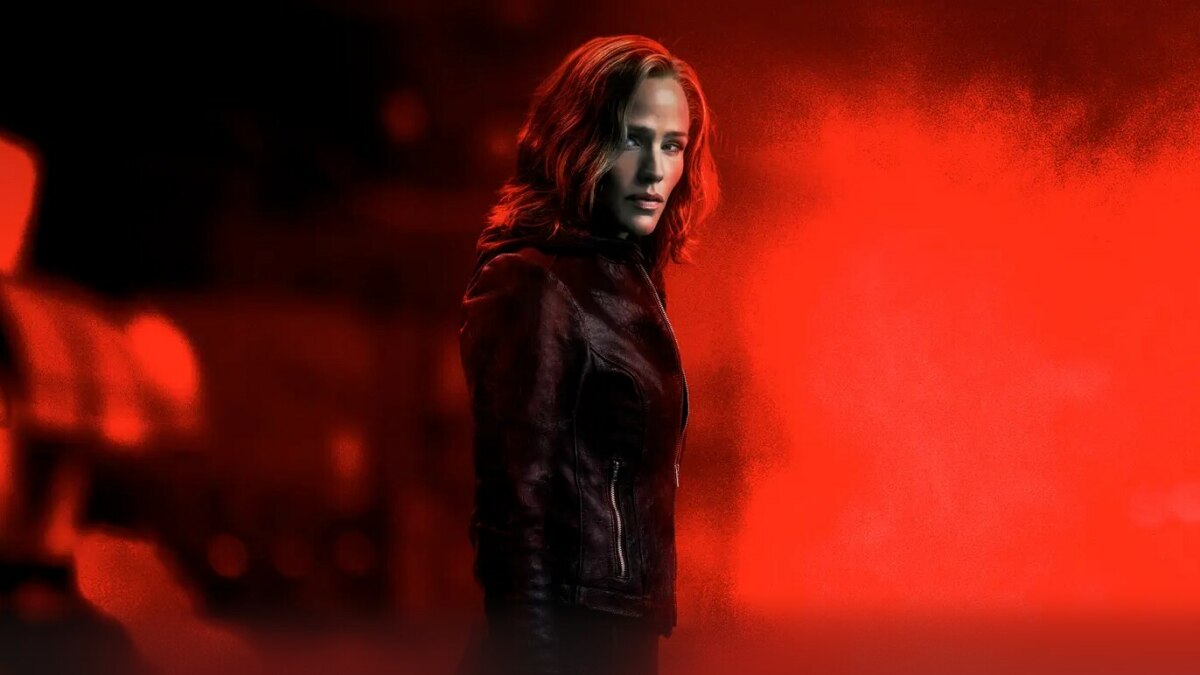Jennifer Garner com roupa escura em um fundo vermelho escuro na divulgação de A Justiceira