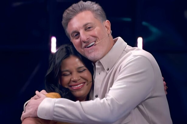 Luciano Huck abraça Eliza no palco do Quem Quer Ser Um Milionário no Domingão. Ela está sorrindo
