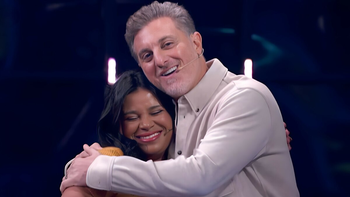 Luciano Huck abraça Eliza no palco do Quem Quer Ser Um Milionário no Domingão. Ela está sorrindo