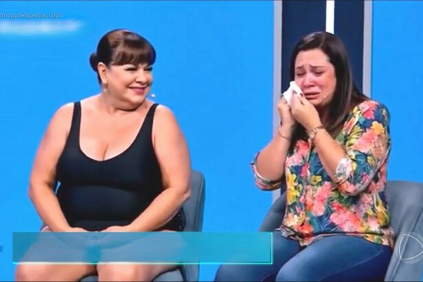 Mulher criada por IA, usa maiô e olha para o lado onde uma entrevistada chora no Programa Marisa Maiô