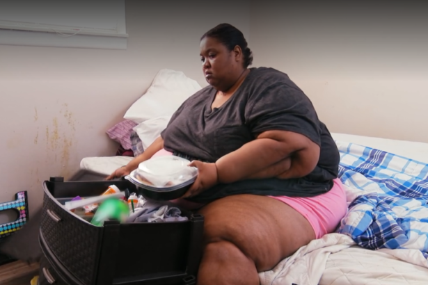 Kelly comendo em cima da cama em cena do Quilos Mortais