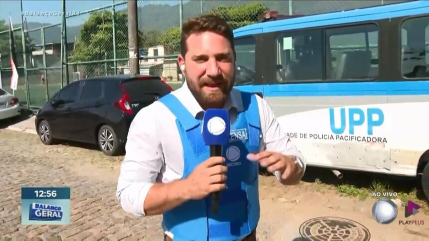 Rael Policarpo segura microfone da RECORD em uma rua do Rio de Janeiro ao lado onde acontece um acidente com duas motos
