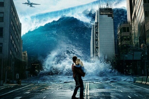 Cena de homem segurando uma mulher no colo correndo de uma grande tempestade de água que invade uma avenida no filme Tempestade: Planeta em Fúria