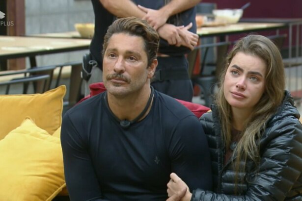 Victor e Rayanne sentados no sofá amarelo da Mansão olham atentamente para o telão onde está Felipe Andreoli antes de anunciarem veto na Prova dos Casais