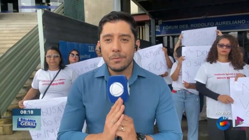 Anderson Souza segura o microfone da RECORD e faz sinal de gratidão com as mãos ao se despedir da TV Guararapes. Ele veste camisa de botão azul e e está emocionado