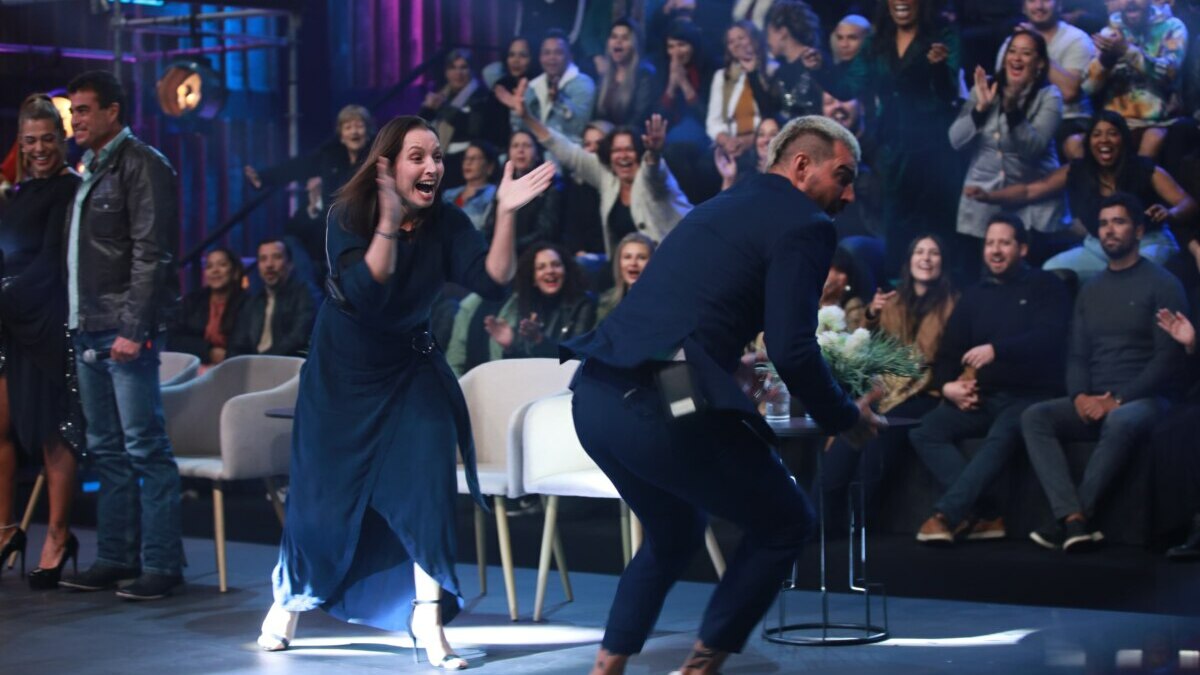 Carol batendo palmas e Radamés correndo de alegria no palco da final do Power Couple Brasil 7