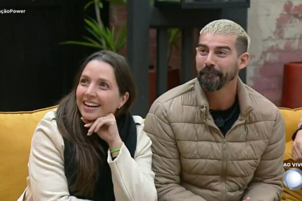 Carol e Radamés sentados no sofá ao acompanhar o resultado da Prova dos Casais no Power Couple