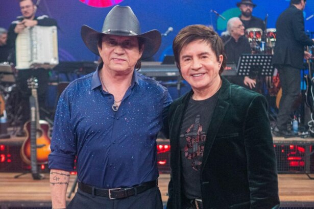Cantores Chitãozinho e Xororó abraçados, em foto posada, em frente a banda, no cenário do Altas Horas