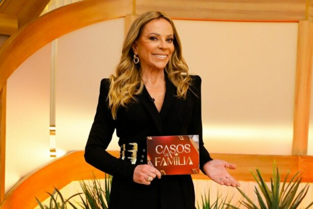 Christina Rocha sorridente, com a ficha do Casos de Família na mão, em foto posada no cenário da nova temporada do programa