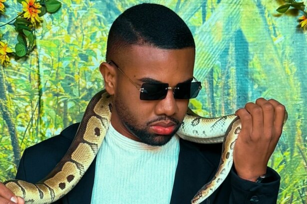 Davi Brito com uma cobra nos braços e óculos escuros