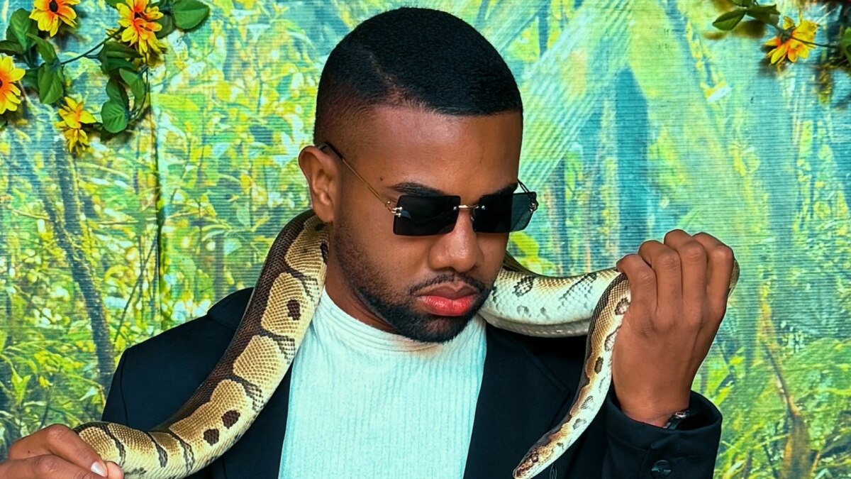 Davi Brito com uma cobra nos braços e óculos escuros