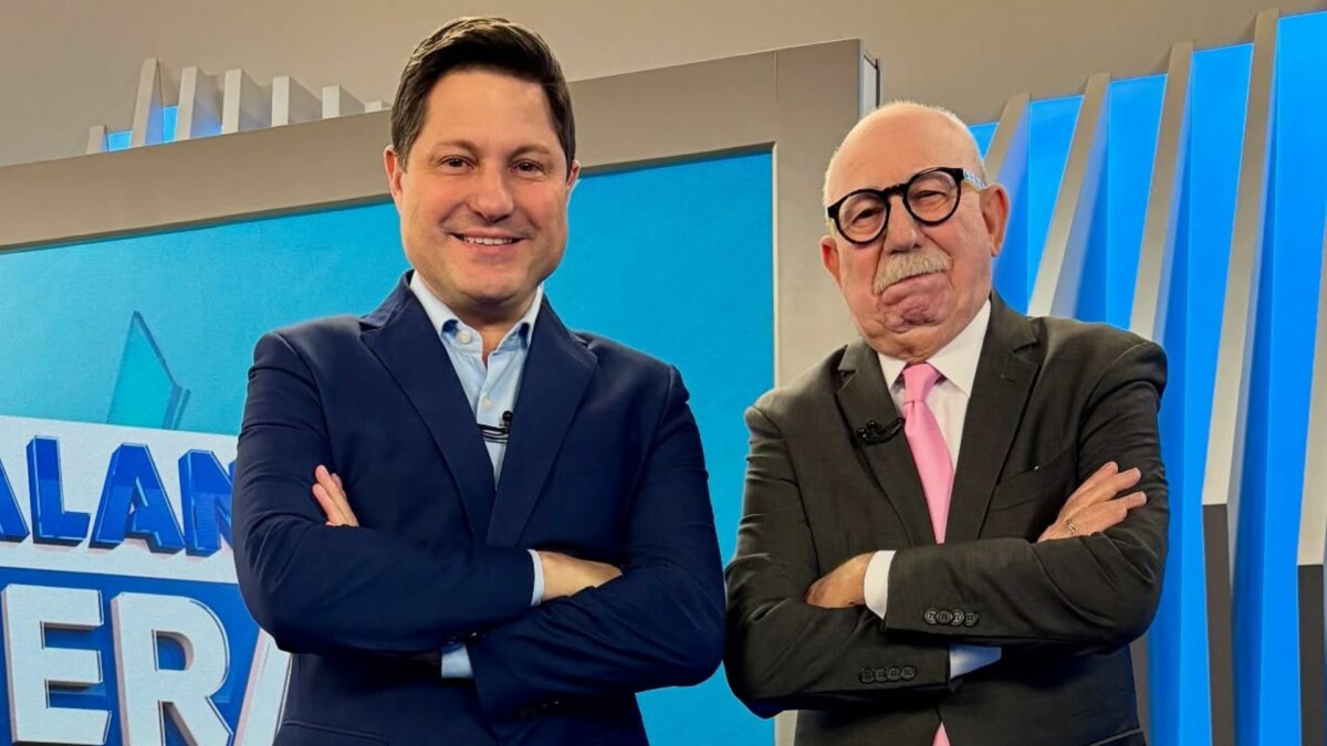 Eleandro Passaia e Renato Lombardi, de braços cruzados e sorridente, no cenário do Balanço Geral