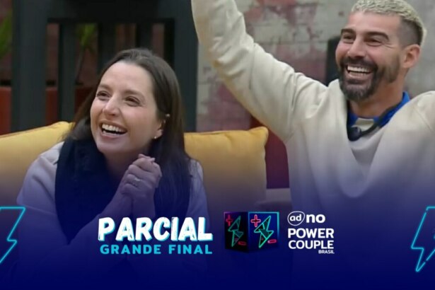 Carol e Radamés comemoram final do Power Couple Brasil 7. Ela está comas mãos unidas sentada no sofá ao lado de Radamés com as mãos levantadas