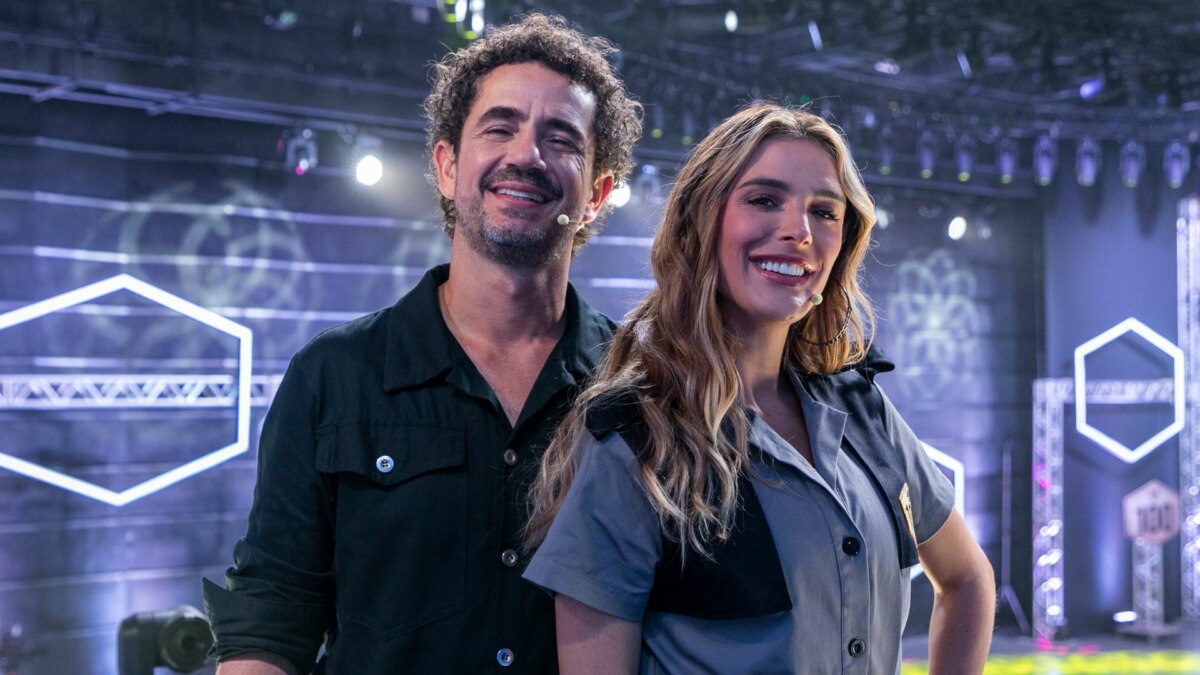 Felipe Andreoli e Rafa Brites sorrindo, em foto posada no cenário do Game dos 100