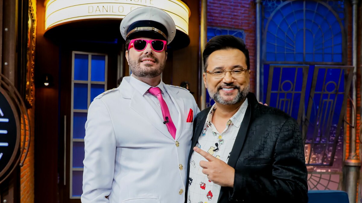 Geraldo Luís e Danilo Gentili sorridentes, em foto posada no cenário do The Noite
