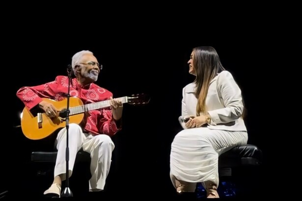 Gilberto Gil toca violão ao lado da filha Preta Gil. Os dois se olham emocionados no palco