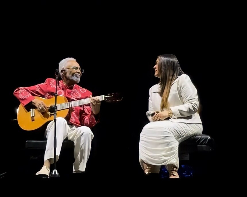Gilberto Gil toca violão ao lado da filha Preta Gil. Os dois se olham emocionados no palco