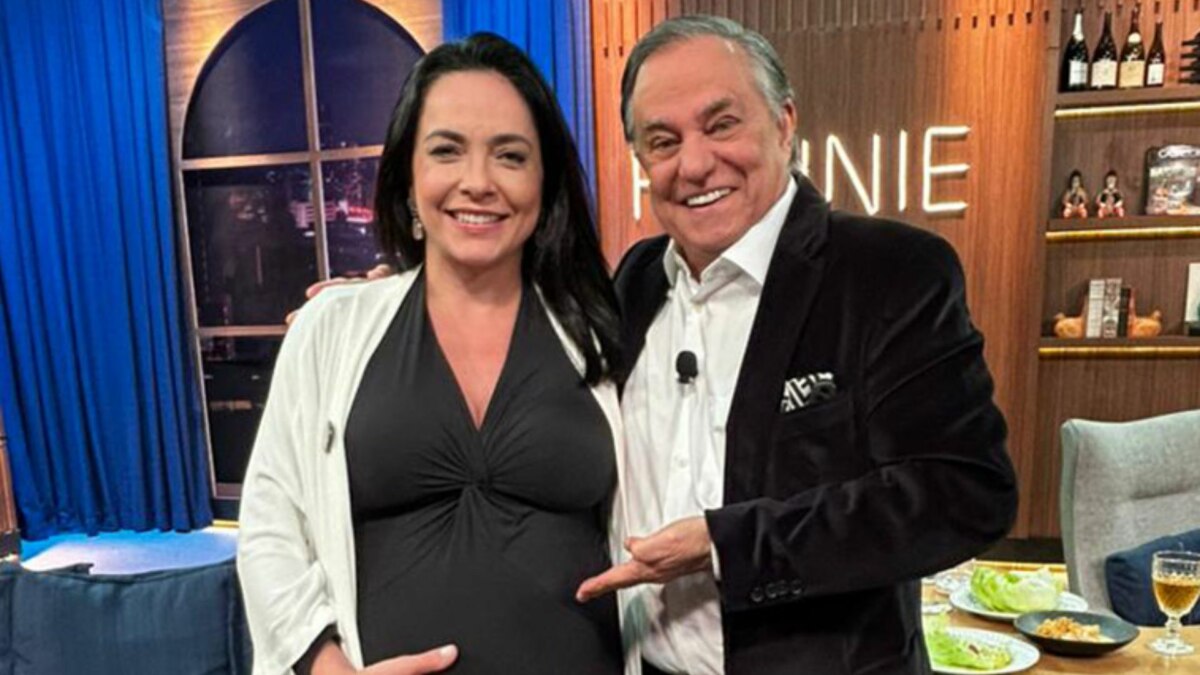 Izabella Camargo, que está grávida, e Ronnie Von em foto posada no cenário do Companhia Certa