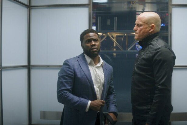 Homem negro olha para um homem branco careca em um elevador em cena do filme O Home de Toronto