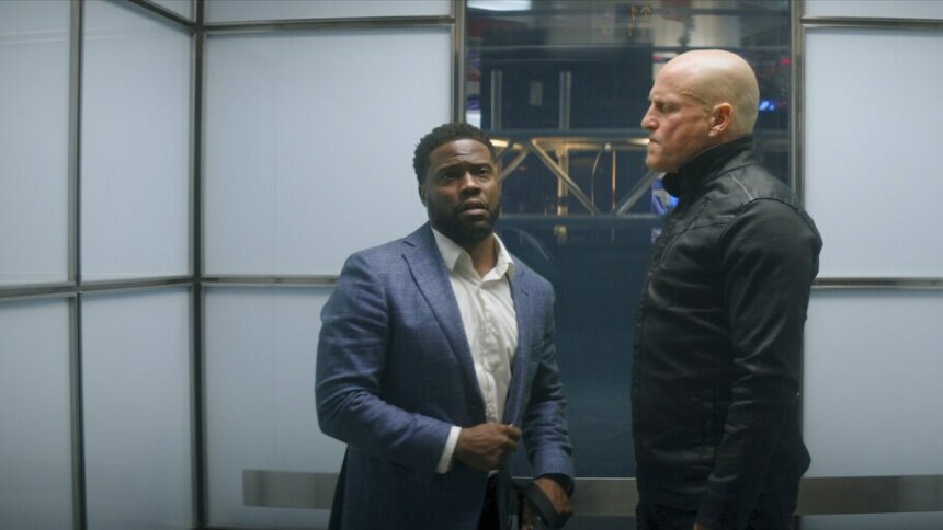 Homem negro olha para um homem branco careca em um elevador em cena do filme O Home de Toronto