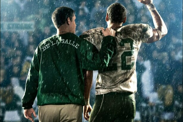 Dois homens de costas em um campo de futebol. Eles vestem roupas de time nas cores verde a branco em cena do filme O Jogo de Uma Vida