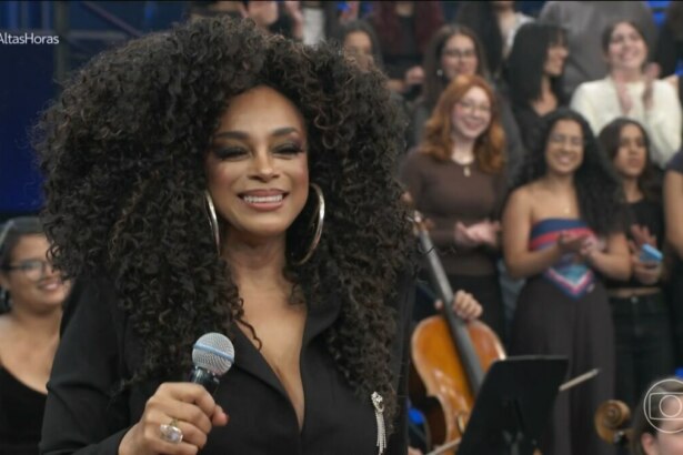 Paula Lima sorrir e segura o microfone no palco do altas Horas