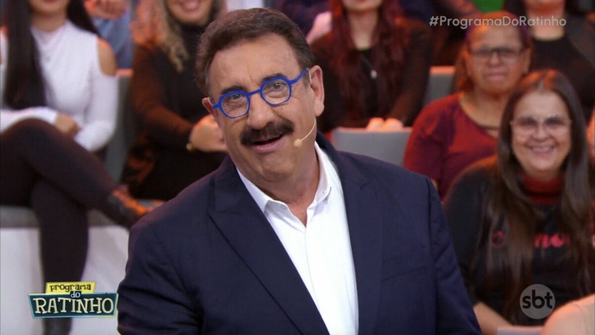 Ratinho, de blazer e óculos, em frente a plateia, em trecho do Programa do Ratinho em trecho de edição que bateu a RECORD