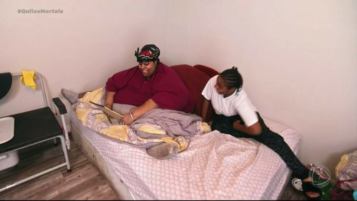 Mercedes sentada em uma cama ao lado de sua filha