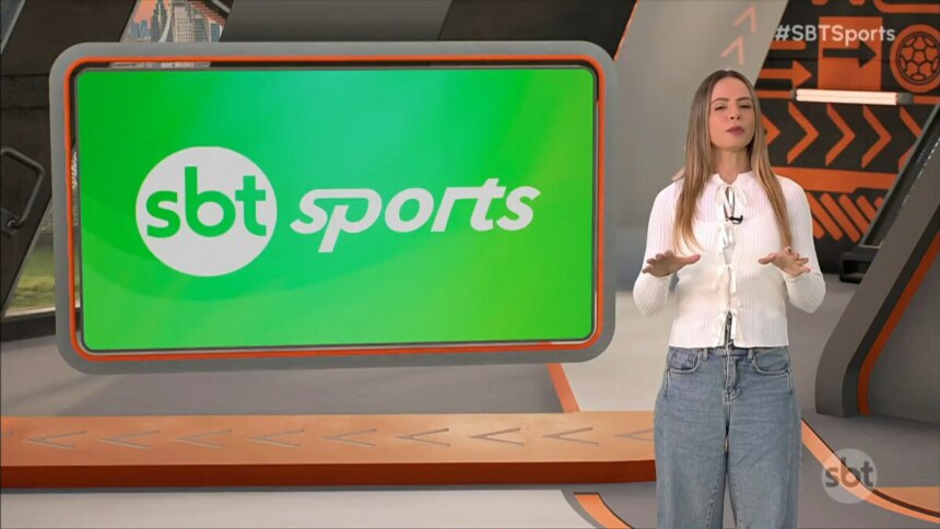 Renata Saporito veste branco e uma calça jeans ao lado do logo do SBT Sports