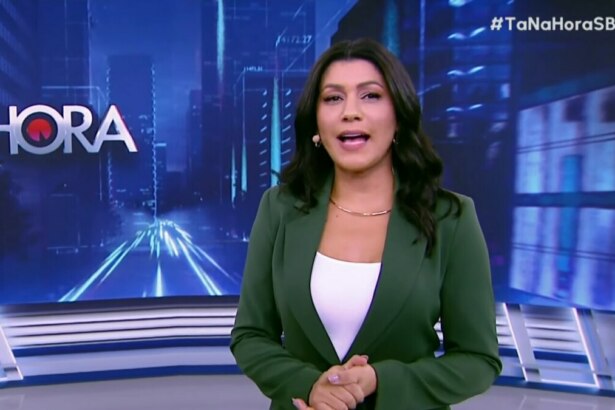 Daniele Brandi, em frente ao telão, em trecho do programa Tá na Hora